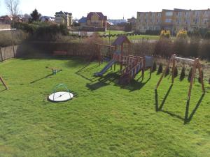 a playground in a yard with a surfboard on the grass at Apartament Maxim in Darłówko