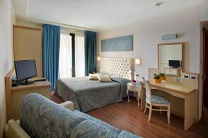 a hotel room with two beds and a desk at Hotel La Rondine in Sirmione