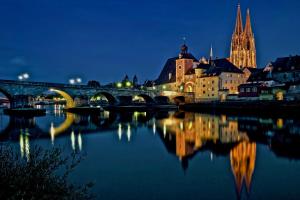 un ponte su un fiume in una città di notte di Ferienwohnung am Herzogspark a Ratisbona