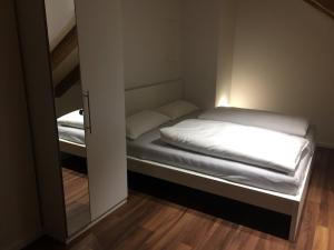 una piccola stanza con un letto e uno specchio di Ferienwohnung am Herzogspark a Ratisbona