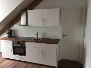 una cucina con mobili bianchi e un lavandino di Ferienwohnung am Herzogspark a Ratisbona Altre 9 foto