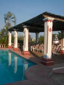 a swimming pool with chairs and a pavilion at Hotel Paraiso Escondido in Puerto Escondido