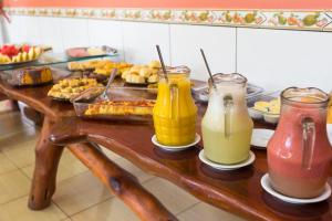 a table with drinks on it with a buffet of food at Pousada Recanto da Concha in Itacaré