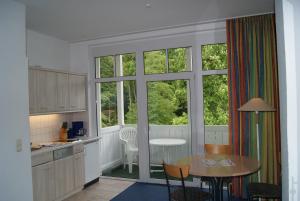a kitchen with a table and chairs and a table and windows at Studio 23, Residenz Seeblick in Ostseebad Sellin