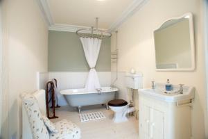 a bathroom with a tub and a toilet and a sink at Dromore House Historic Country house in Coleraine