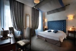 シャル・レ・ゾーにあるシャトー デ コント ド シャルの大きなベッドとデスクが備わるホテルルームです。