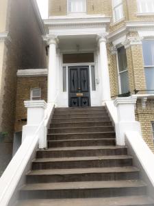 a staircase leading to a house with a black door at The Studio - Heart Of Primrose Hill in London