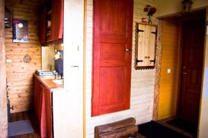 a kitchen with a red door in a wooden cabin at Salme Apartment in Tartu