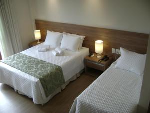 a hotel room with two beds and two lamps at Flat Particular Pedra Azul in Pedra Azul