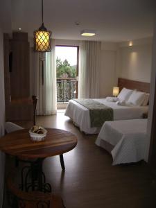 a hotel room with two beds and a table at Flat Particular Pedra Azul in Pedra Azul