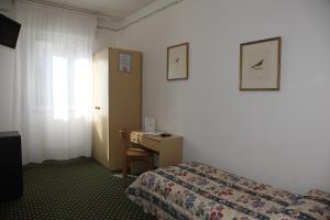 a bedroom with a bed and a desk and a window at Hotel Villa Rosa in Grado