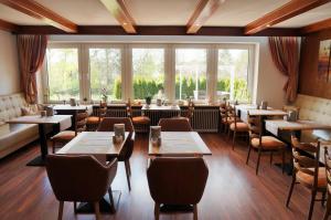 ein Restaurant mit Tischen und Stühlen und einem großen Fenster in der Unterkunft Hotel Diana Garni in Malente
