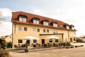 a building with tables and chairs in front of it at Hotel & Restaurant Zum Hirsch in Römhild