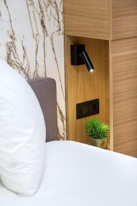 1 dormitorio con cama blanca y planta en Aegli Hotel Volos, en Volos