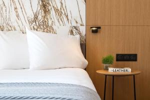 a bed with white sheets and a table with a nightstand at Aegli Hotel Volos in Volos