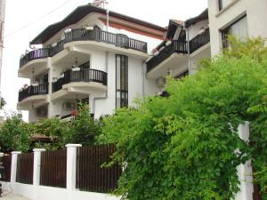 a white building with balconies and a fence at Guest House Starata Kushta in Lozenets