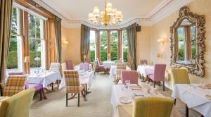 ein Restaurant mit Tischen, Stühlen und einem Kronleuchter in der Unterkunft Knockendarroch Hotel in Pitlochry