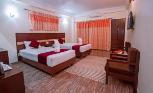 een hotelkamer met twee bedden en een televisie bij Hotel Spring in Pokhara