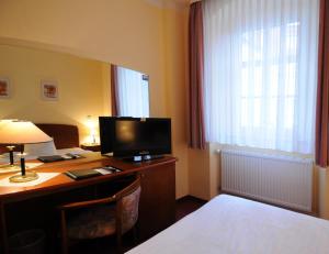 a hotel room with a desk with a computer and a bed at Hotel Döbelner Hof in Döbeln