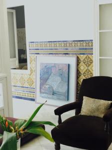 a living room with a chair and a painting at Casa Bolsa43 in Sanlúcar de Barrameda