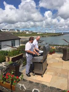 two men cooking on a grill on a patio at Port Charlotte Hotel in Port Charlotte