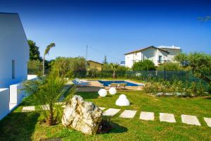 a backyard with a yard with a rock and a pool at Baia degli Ulivi Apartments in Cefalù