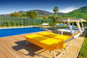 a deck with a pool and a yellow lounge chair at Baia degli Ulivi Apartments in Cefalù