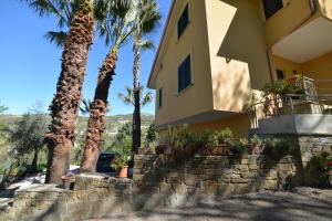 una casa amarilla con palmeras y una pared de retención en La Locanda di Campagna, en Agropoli