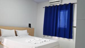 um quarto com 2 camas e uma cortina azul em Hotel Cavalo Marinho Suítes em Caraguatatuba