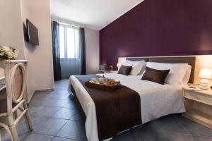 a bedroom with a large bed with a purple wall at Hotel Soleluna in Piano di Sorrento