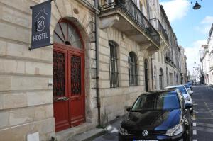 samochód zaparkowany obok budynku z czerwonymi drzwiami w obiekcie HOSTEL20 Bordeaux HIFRANCE w mieście Bordeaux