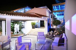 a patio with purple chairs and a table and a building at Hotel Años 50 in Torremolinos