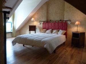 een slaapkamer met een groot bed met een rood hoofdeinde bij La Guichardière in Vay