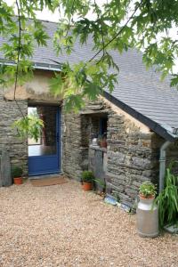 ein Steinhaus mit einer blauen Tür und Topfpflanzen in der Unterkunft La Guichardière in Vay