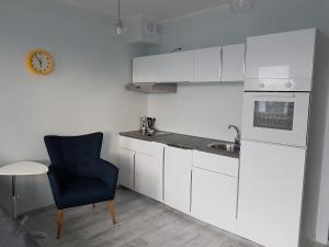 a kitchen with white cabinets and a blue chair and a sink at Cukrownia in Szczecin