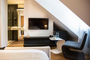 a living room with a tv and a couch and a chair at Hotel Nicolaus in Toruń