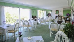 une salle à manger avec des tables et des chaises blanches dans l'établissement Villa Ric, à Saint-Céré