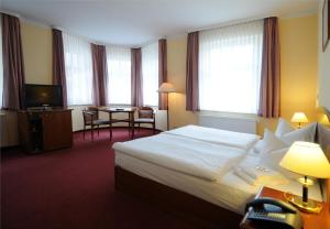 ein Hotelzimmer mit einem Bett und einem Tisch in der Unterkunft Hotel Döbelner Hof in Döbeln