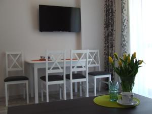 mesa de comedor blanca con sillas y TV en la pared en ApartHotel Admirał, en Iława
