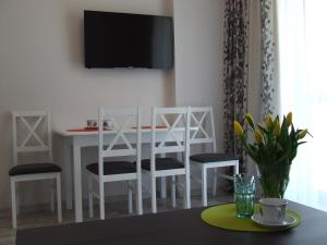 een witte eettafel met stoelen en een tv aan de muur bij ApartHotel Admirał in Iława