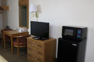 a room with a television on a dresser with a small refrigerator at Highland Country Inn Flagstaff in Flagstaff