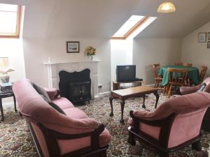 a living room with two chairs and a fireplace at Mellottes Self Catering in Cornamona