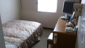 1 dormitorio con 1 cama y escritorio con ordenador en Hotel New Budget Sapporo, en Sapporo