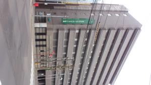 a tall building with a green street sign on it at Hotel New Budget Sapporo in Sapporo