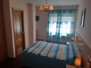 1 dormitorio con 1 cama con cortina y ventana en Casa Poy, en Becerreá