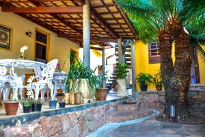 a patio with palm trees and chairs and plants at Pousada Solar Azul in Lençóis
