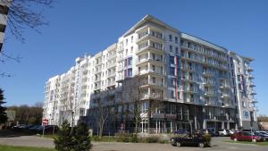 コウォブジェクにあるApartament Kolobrzegの白い大型アパートメントで、駐車場に駐車しています。
