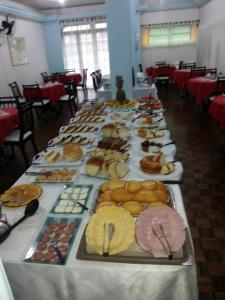 una mesa larga llena de diferentes tipos de repostería en Hotel Tourist Araranguá, en Araranguá