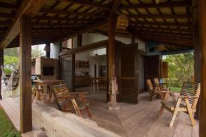 a large wooden deck with wooden chairs and tables at Surf a poucos passos do mar, casa com lareira in Garopaba