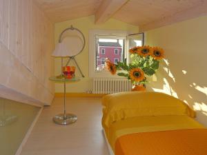 Un dormitorio con una cama amarilla y un jarrón de girasoles en Casa Nova en Burano